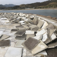 強風で地面のタイルがバラバラに吹き飛ばされた海辺の公園